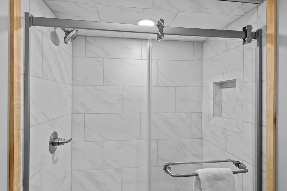 A bright, modern bathroom featuring a glass shower enclosure, contemporary shower head, and towel rack. The clean lines and light colors evoke a sense of refreshment and relaxation.